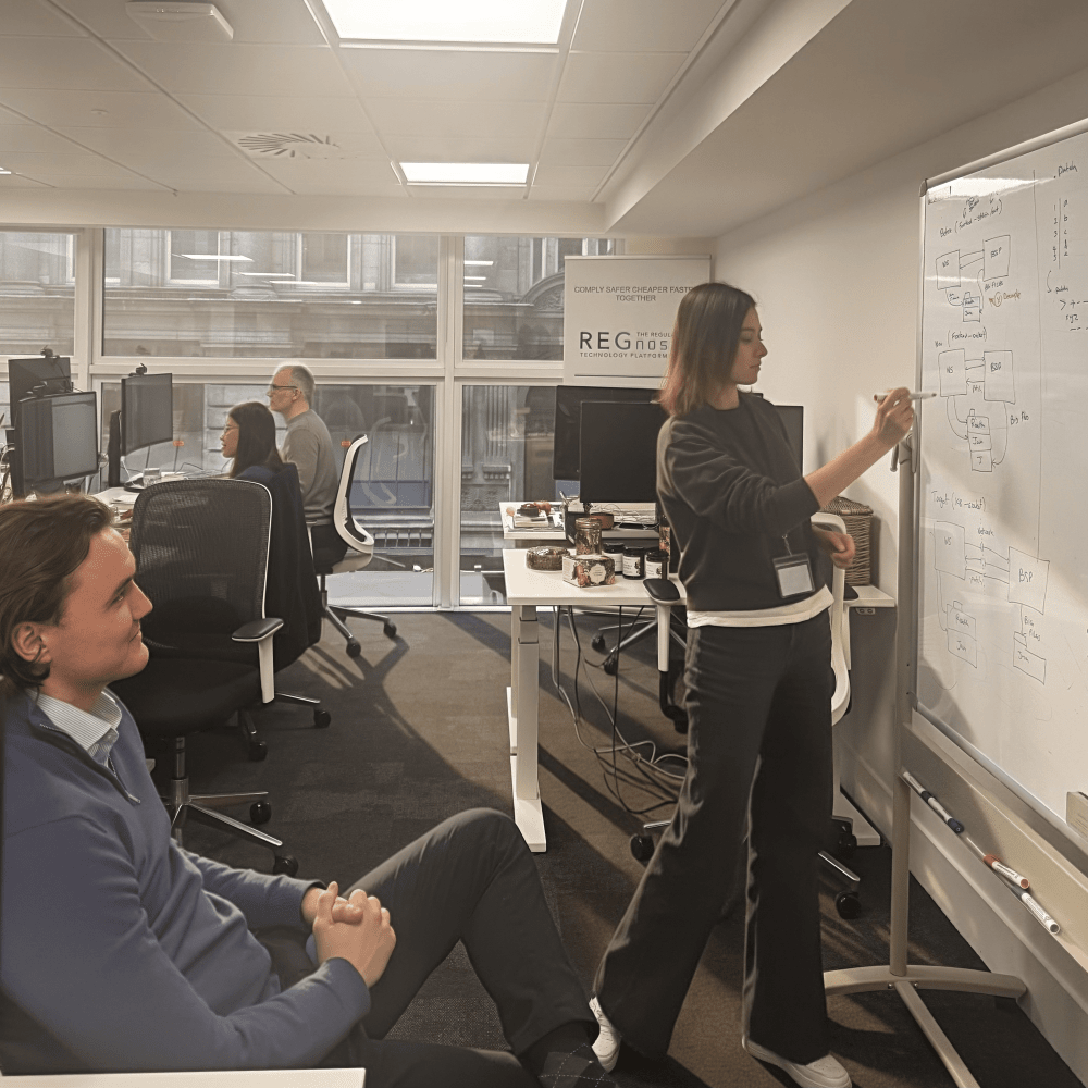 Alona writing on a white board in a team meeting