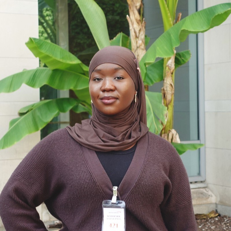 Hawwah, a young Black hijabi woman and NTG community member, smiles at the camera