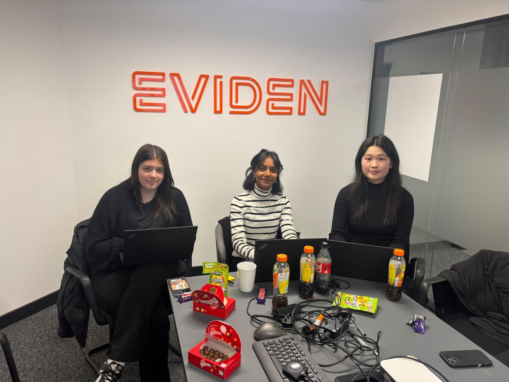 Three women sit at a desk in the Eviden office