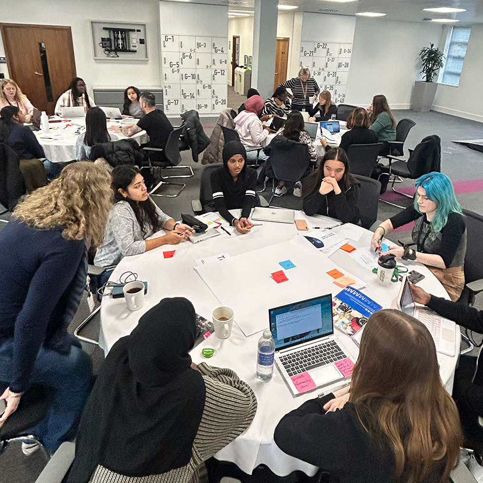 Groups of young women sat round tables with laptops and post-it notes during the Next Tech Girls and Motability Operations hackathon in Bristol.