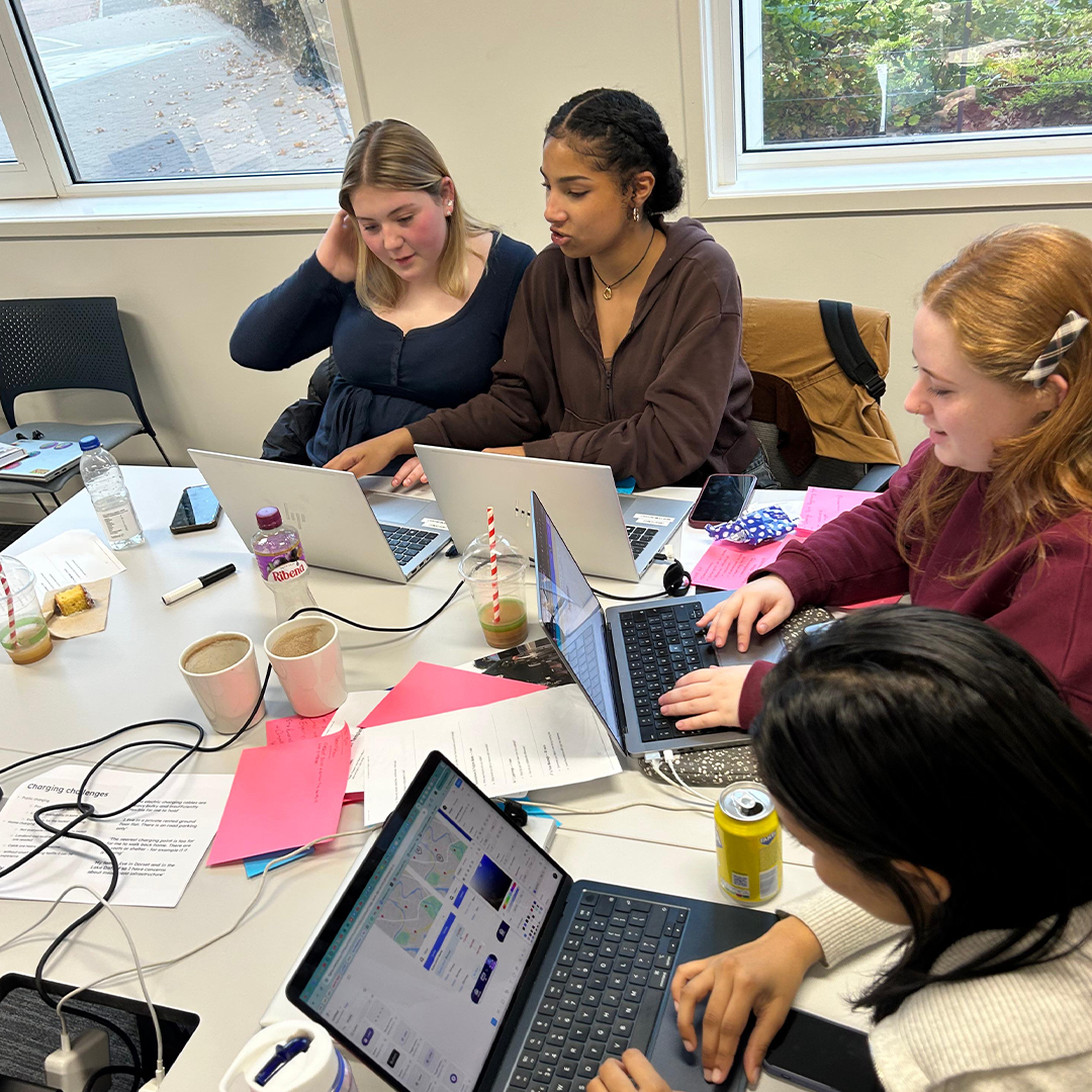 A group of young women sat round desks with laptops during the Next Tech Girls and Motability Operations hackathon in Edinburgh.