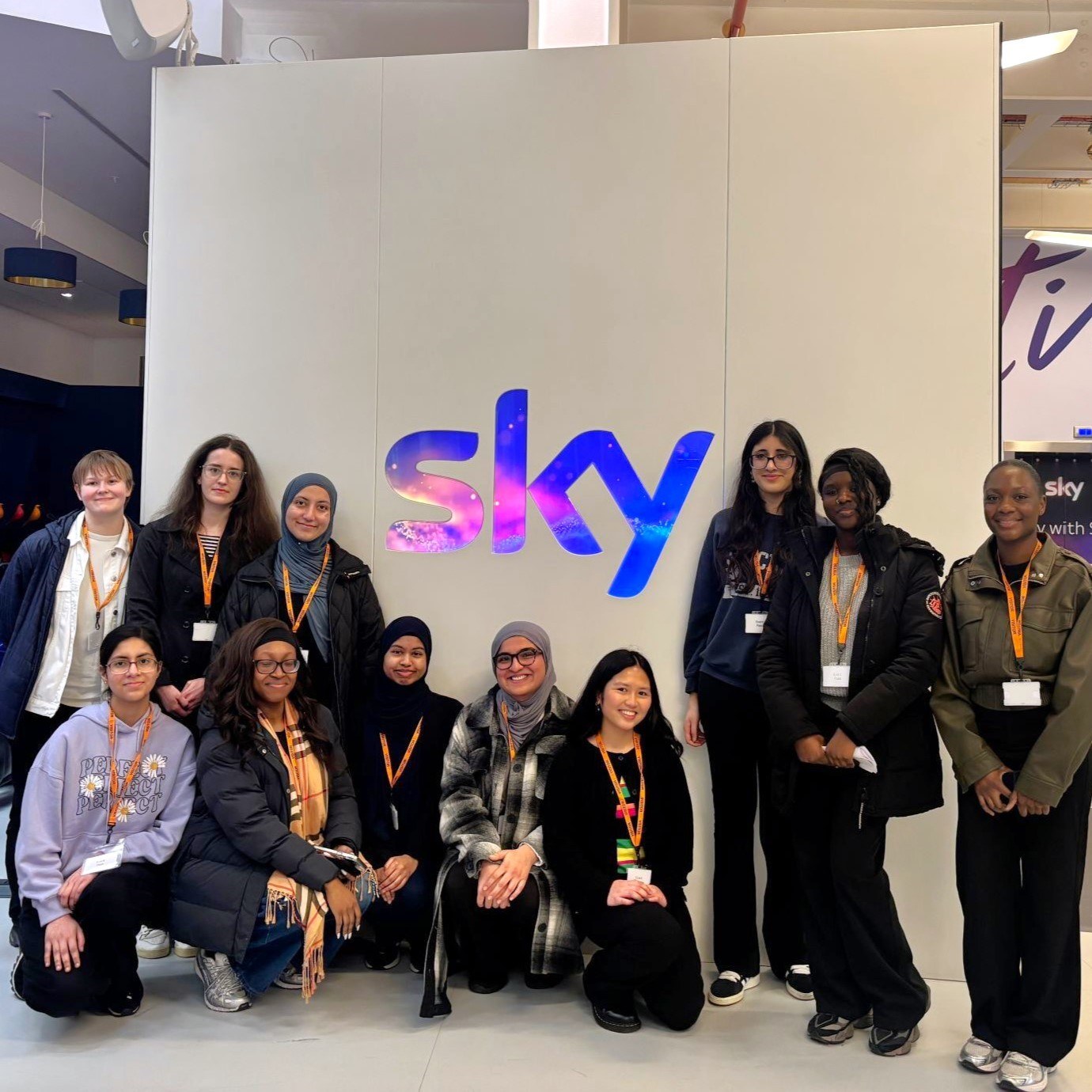 A group of young women posing next to a Sky sign at a Next Tech Girls Insight Day