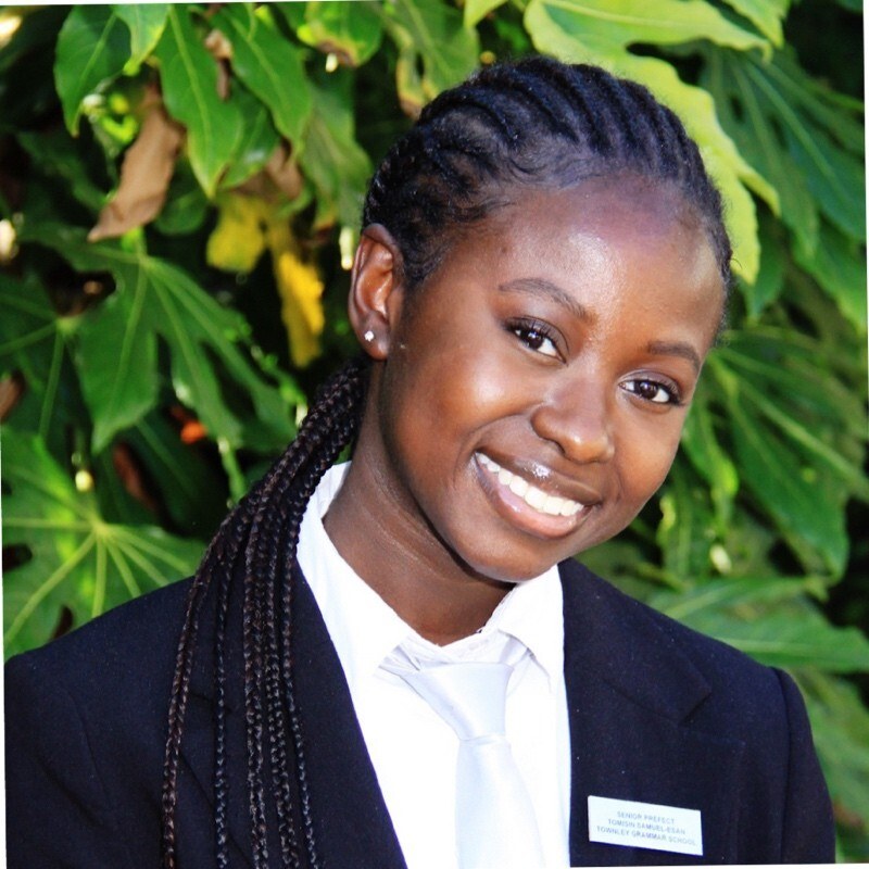 A photo of Tomisin, a young Black woman and member of the NTG community, smiling.