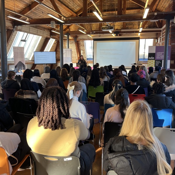 The backs of around 50 young women's heads as they sit in the audience watching a presentation at the Next Tech Girls and Mastek Insight Day in Manchester.