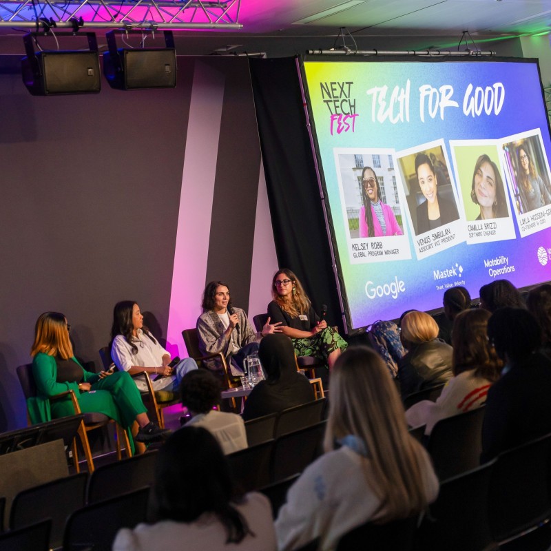 Camilla from Motability Operations talks into a microphone on stage alongside four other women at Next Tech Fest 2025.