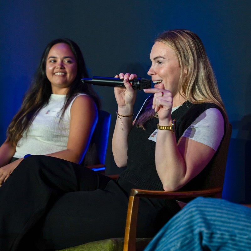 Niamh from ControlPlane smiling and speaking into a microphone on a panel at Next Tech Fest 2025.
