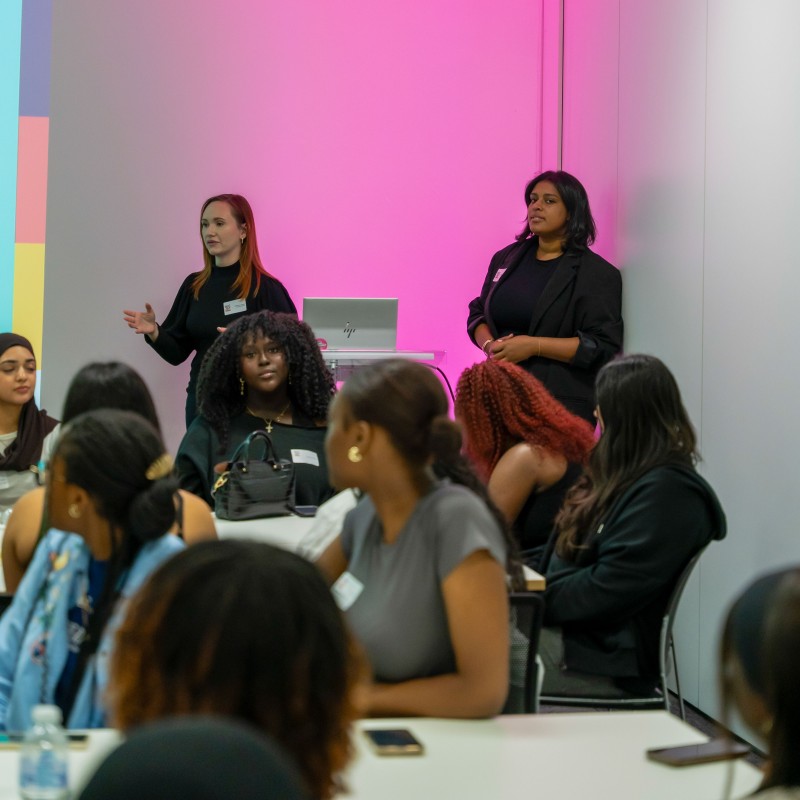 Two women from Publicis Media run a workshop for a room full of young women.