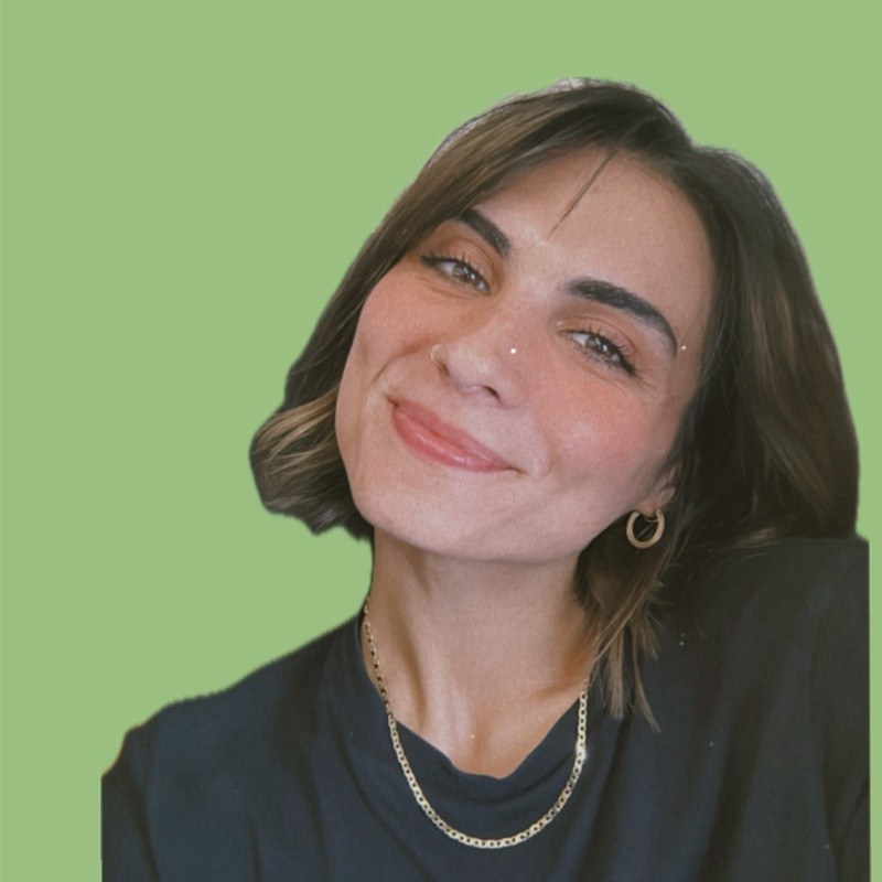 A headshot of a young woman with short brown hair looking directly at the camera against a plain green background.